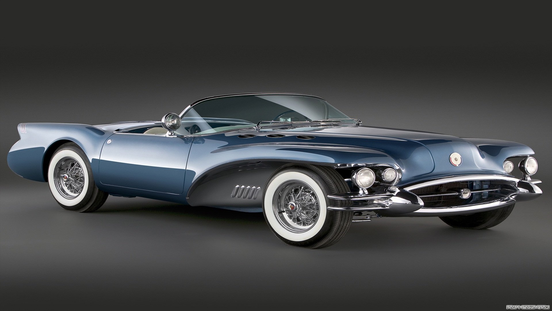 HD desktop wallpaper featuring a sleek 1954 Buick Wildcat Convertible in glossy blue against a dark gradient background.