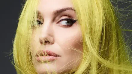 Close-up portrait of a woman with vivid yellow hair and winged eyeliner, soft skin tones, gazing off-frame — 4K Ultra HD PC desktop wallpaper/background.