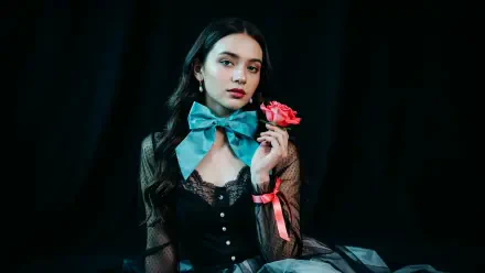 Dark coquette portrait of a woman in lace with a turquoise bow, holding a pink rose against a black backdrop — 4K Ultra HD PC desktop wallpaper background.