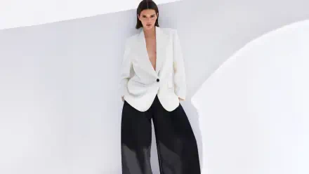 8K Ultra HD PC desktop wallpaper of a celebrity model in a white blazer and wide black trousers posed against a minimalist white backdrop