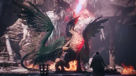 Dragon's Dogma 2 HD PC desktop wallpaper/background: a towering dragon with wings spread, roaring amid icy stalactites and fire in a cavern as a lone cloaked figure faces it.