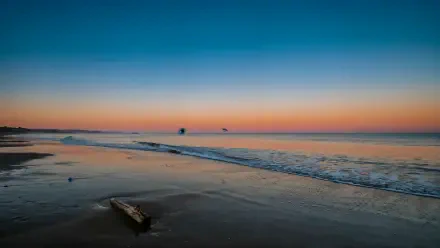 4K Ultra HD PC desktop wallpaper of a quiet ocean shore at sunset, with gentle waves washing across the beach.