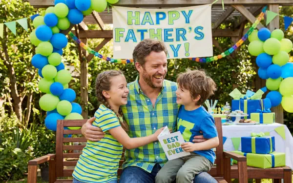 5K Ultra HD PC desktop wallpaper and background: smiling father sits outdoors with two children hugging under a 'Happy Father's Day' banner, surrounded by balloons and wrapped gifts.