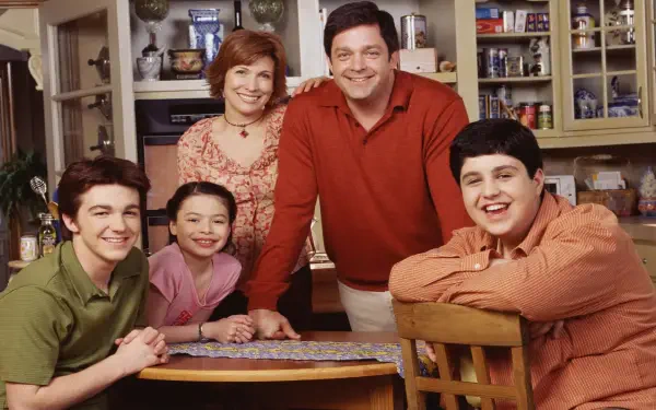 Drake & Josh HD PC desktop wallpaper: cast family portrait in a cozy kitchen, two teen boys and their parents smiling around a table.