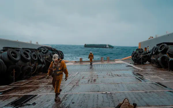 5K Ultra HD PC desktop wallpaper: men in yellow suits on a ship deck, ocean ahead and a SpaceX Starship resting on the water.