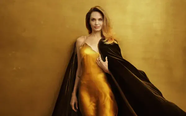 Glamorous portrait of a woman in a golden satin gown and dark cloak against a warm gold backdrop, 4K Ultra HD PC desktop wallpaper.