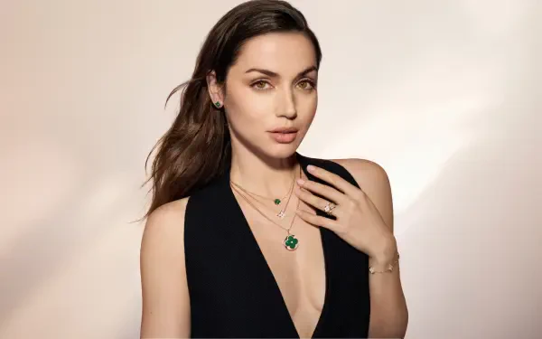 8K Ultra HD PC desktop wallpaper: portrait of a female celebrity actress in a black deep-V dress, wearing emerald jewelry against a soft neutral backdrop.