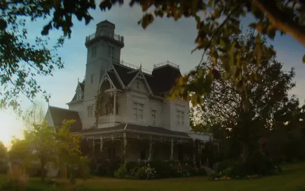 Victorian Owens House mansion from Practical Magic 2 at sunset, framed by trees — 2K Quad HD PC desktop wallpaper background.