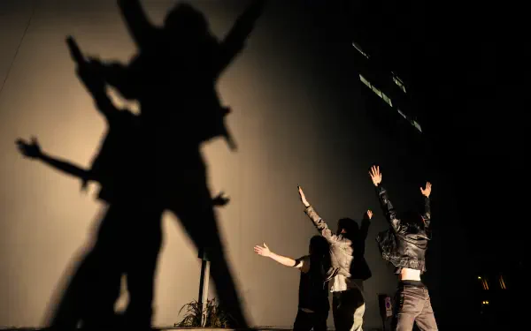 Cortis fashion performers cast dramatic silhouettes and shadows on a backlit wall — 4K Ultra HD PC desktop wallpaper/background.