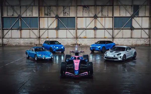 Alpine A526 race car with sports cars in an industrial garage, featured in an 8K Ultra HD PC desktop wallpaper background.