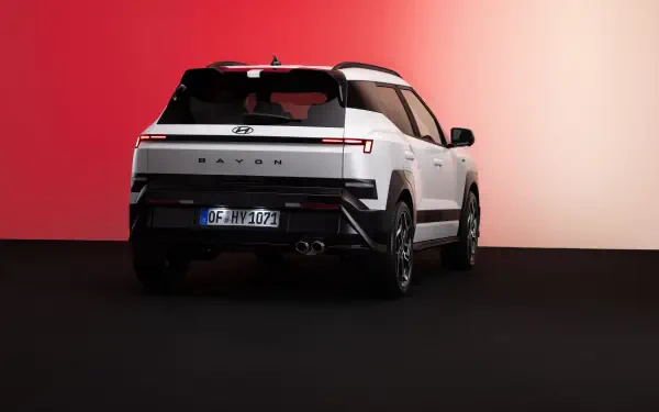 8K Ultra HD desktop wallpaper of a white Hyundai Bayon SUV viewed from the rear against a red and white studio backdrop.