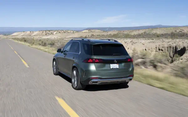 Mercedes-Benz GLS SUV driving along a scenic desert road, featured in an HD PC desktop wallpaper and background.