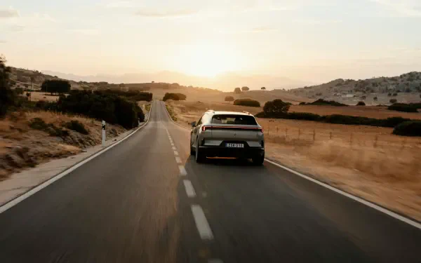 Polestar 4 SUV driving along a winding country road at sunset, featured in a 5K Ultra HD PC desktop wallpaper.