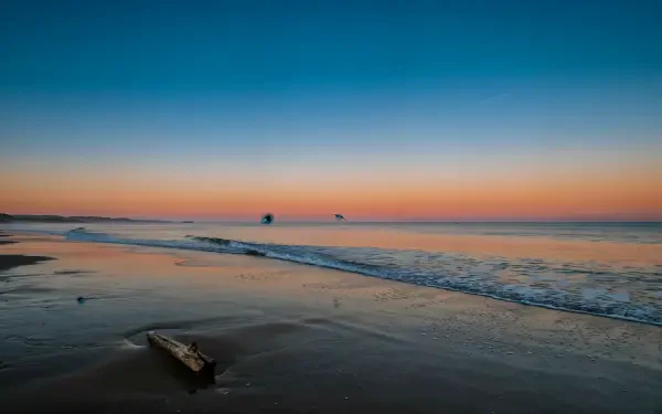 4K Ultra HD PC desktop wallpaper of a quiet ocean shore at sunset, with gentle waves washing across the beach.