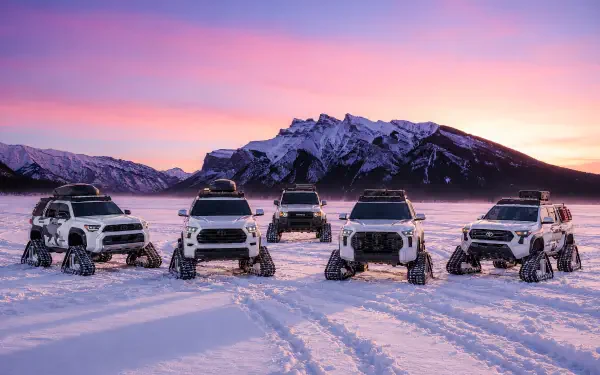 Toyota Snowhunter off-road SUVs on a snowy mountain plain at sunset, featured in a 2K Quad HD desktop wallpaper background.