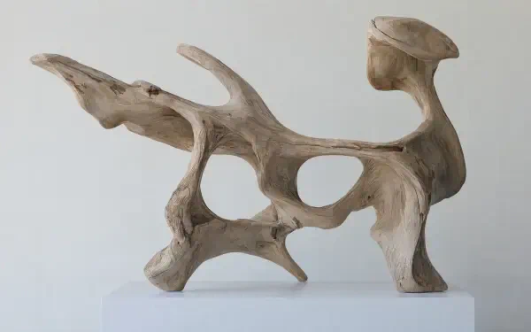 Abstract driftwood wood sculpture on a white display base, featured in a 4K Ultra HD PC desktop wallpaper and background.