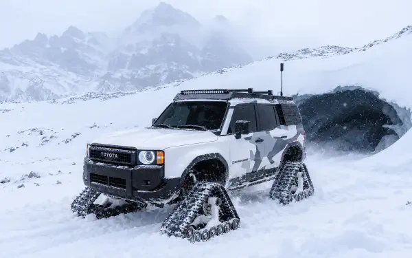 Toyota Land Cruiser Snowhunter off-road SUV with snow tracks crossing a snowy mountain landscape, 2K Quad HD PC desktop wallpaper background.