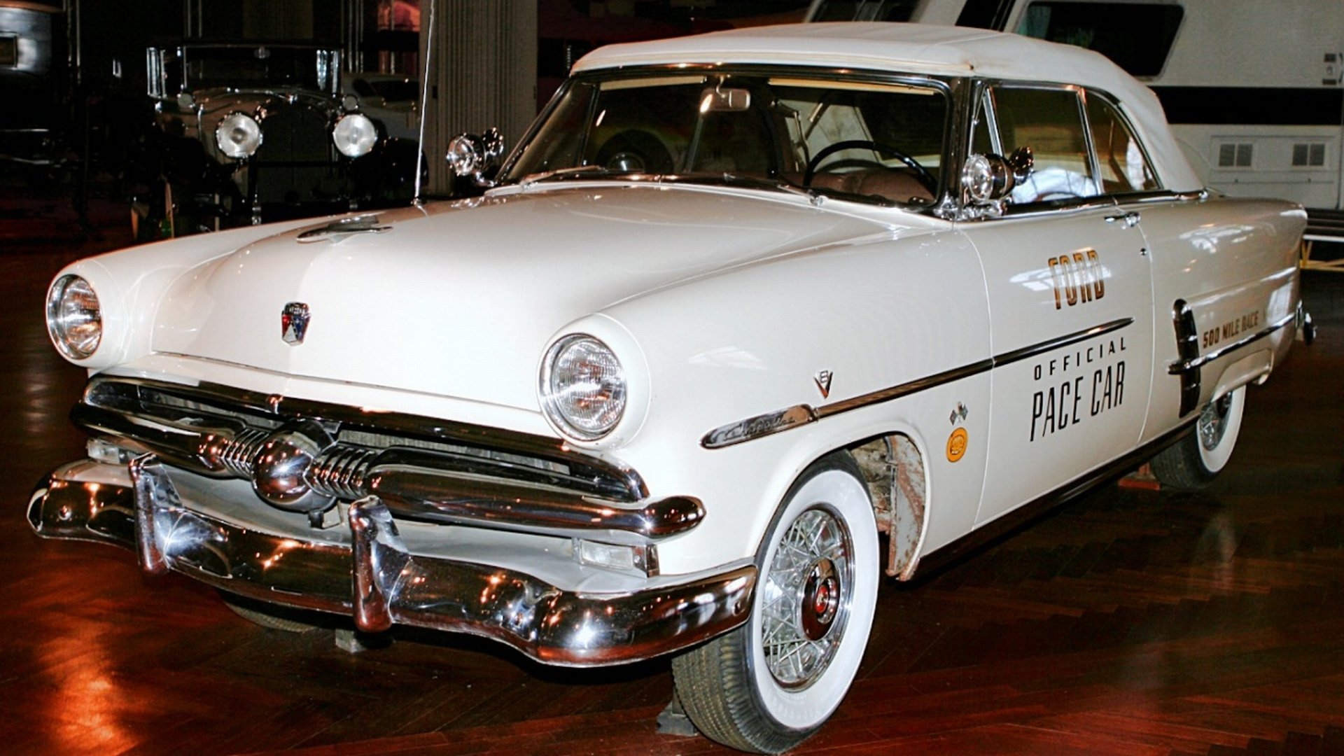 White 1953 Ford Crestline Sunliner Convertible showcased indoors with chrome trim and whitewall tires — HD PC desktop wallpaper background.