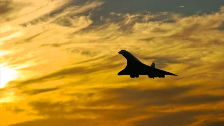 Silhouette of a supersonic aircraft flying against a dramatic orange and yellow sunset sky, captured as an HD PC desktop wallpaper and background.