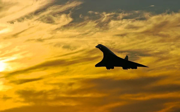 Silhouette of a supersonic aircraft flying against a dramatic orange and yellow sunset sky, captured as an HD PC desktop wallpaper and background.