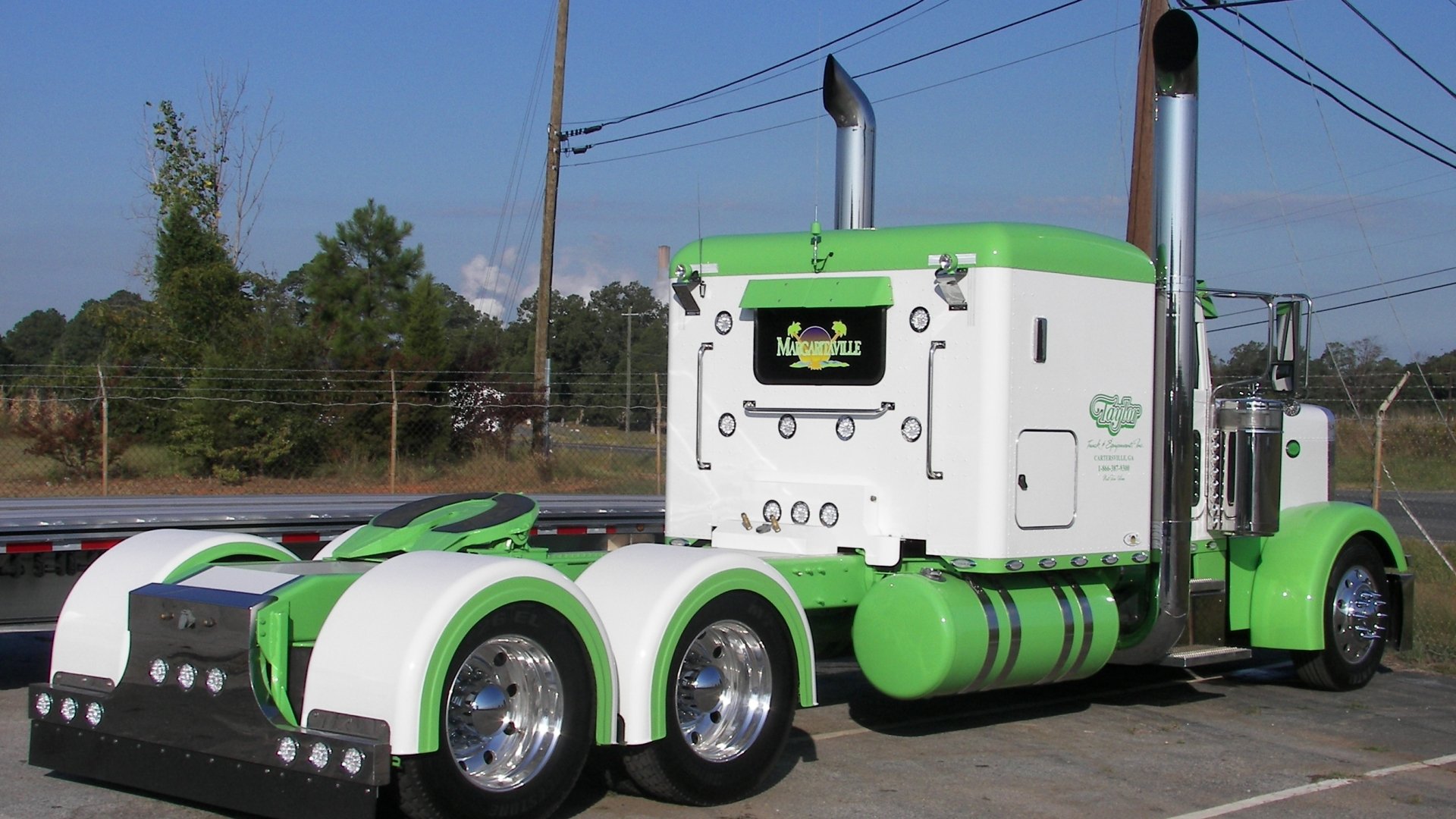 HD PC desktop wallpaper featuring a green and white Peterbilt truck parked outdoors under a clear sky.