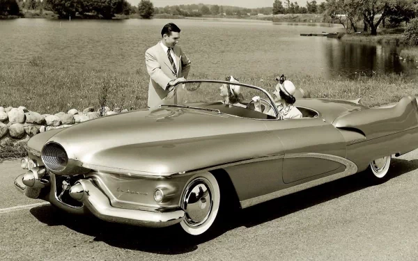 Vintage Buick LeSabre convertible parked by a lakeside, with a man and woman dressed in mid-20th century attire, featured in an HD PC desktop wallpaper background.