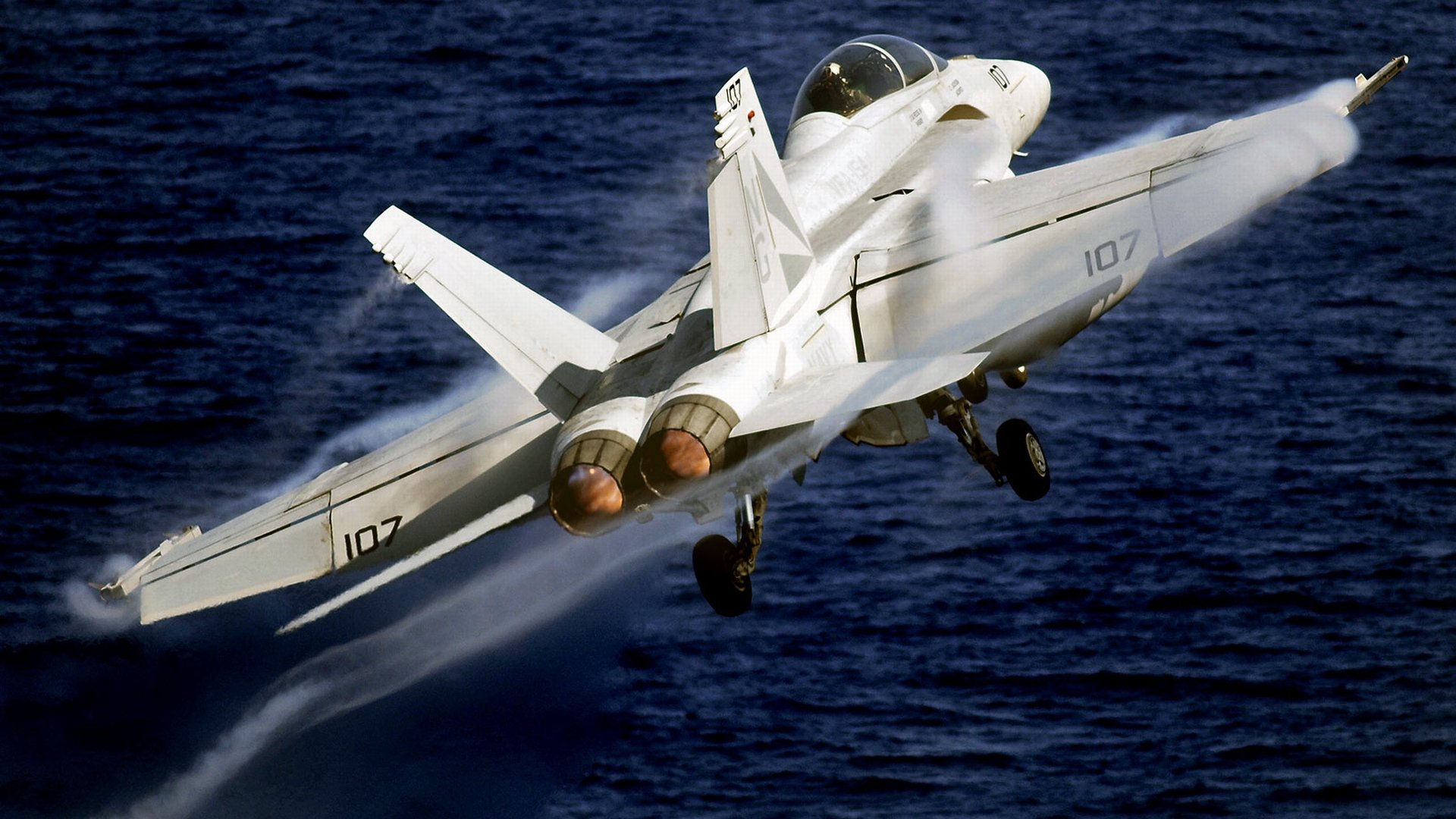 HD desktop wallpaper featuring a McDonnell Douglas F/A-18 Hornet military jet ascending over the ocean.