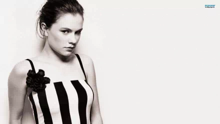 A high-definition desktop wallpaper featuring Anna Paquin, showcasing her in a stylish black-and-white striped dress against a minimalist background.