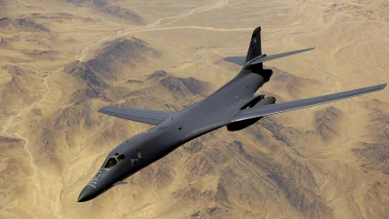 Military Rockwell B-1 Lancer bomber flying over a desert landscape, captured in high definition for a PC desktop background.