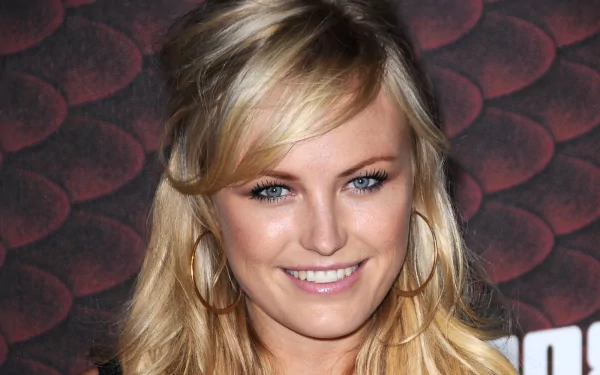 HD PC desktop wallpaper of a smiling blonde female celebrity with blue eyes and hoop earrings, posed against a textured maroon backdrop.