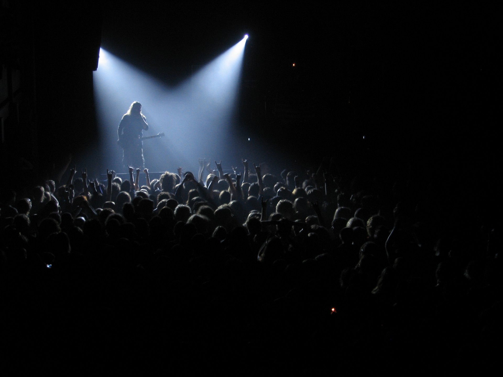 A dynamic concert scene featuring a performer on stage under bright lights, with an enthusiastic crowd below, capturing the energy of Lamb Of God in this striking HD wallpaper.
