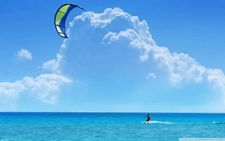 HD PC desktop wallpaper and background: windsurfing sports scene — a lone windsurfer skimming turquoise sea beneath a bright blue sky and towering white clouds.