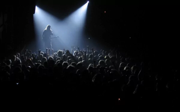A dynamic concert scene featuring a performer on stage under bright lights, with an enthusiastic crowd below, capturing the energy of Lamb Of God in this striking HD wallpaper.