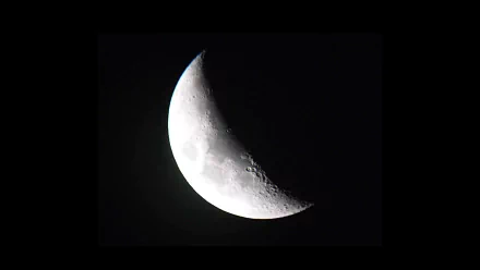 A close-up of a crescent moon against a dark sky, showcasing intricate lunar details. This stunning image serves as a captivating HD nature desktop wallpaper and background.