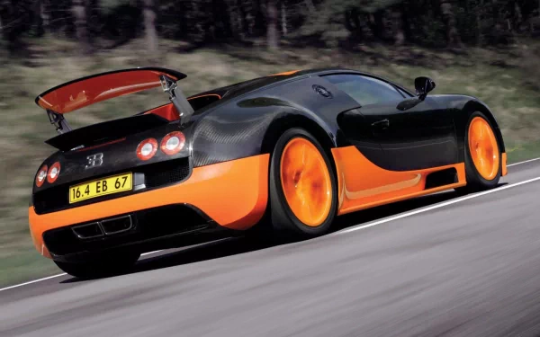 HD desktop wallpaper featuring a black and orange Bugatti Veyron 16.4 Grand Sport speeding on a road with its rear spoiler raised.