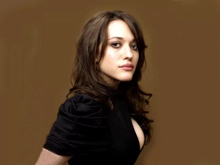 A striking HD desktop wallpaper featuring celebrity Kat Dennings, showcasing her with long hair and a stylish black outfit against a warm brown backdrop.