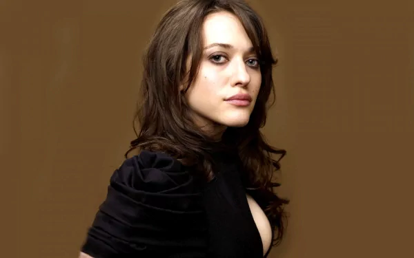 A striking HD desktop wallpaper featuring celebrity Kat Dennings, showcasing her with long hair and a stylish black outfit against a warm brown backdrop.