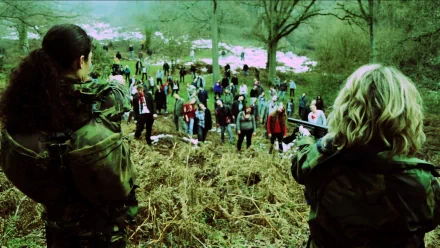 HD PC desktop wallpaper from the movie Zombie Diaries 2: two armed survivors aim at a descending horde of zombies across a grassy hillside under bare trees.