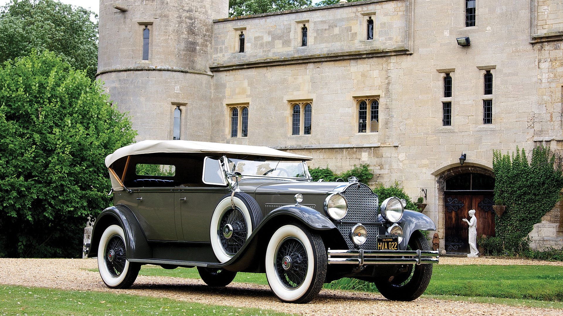 A vintage Packard Deluxe Eight Sport Phaeton car parked in front of an old stone building, featured in an HD PC desktop wallpaper and background.