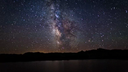 HD desktop wallpaper featuring a Sci-Fi themed view of the Milky Way galaxy sprawling brightly across the night sky above a serene, dark landscape.