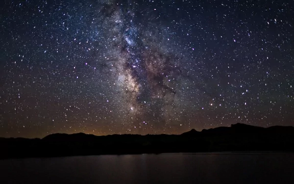 HD desktop wallpaper featuring a Sci-Fi themed view of the Milky Way galaxy sprawling brightly across the night sky above a serene, dark landscape.