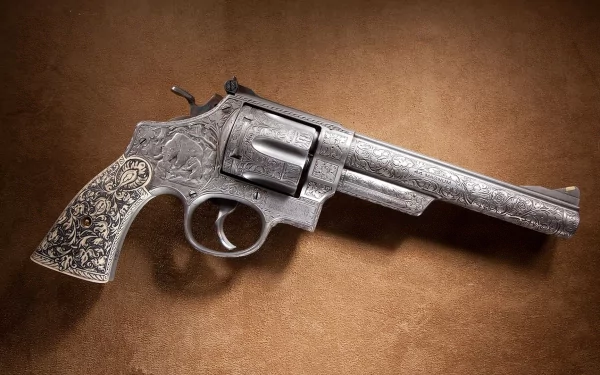 A detailed 44 Magnum revolver rests on a textured brown surface, showcasing intricate engravings that enhance its striking appearance, making it a captivating HD desktop wallpaper.
