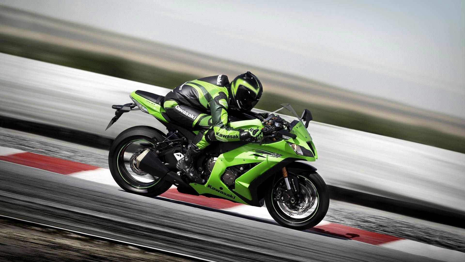 HD desktop wallpaper of a Kawasaki motorcycle speeding on a racetrack, featuring a rider in matching green and black gear.