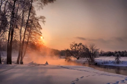 HD PC desktop wallpaper of a serene winter landscape at sunrise, featuring snow-covered ground, bare trees, and mist rising over a calm river in nature.