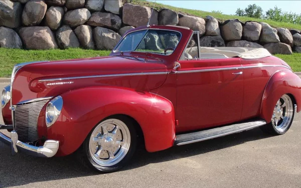 Glossy red vintage Mercury convertible parked on a road before a stone wall, presented as a 4K Ultra HD PC desktop wallpaper/background.
