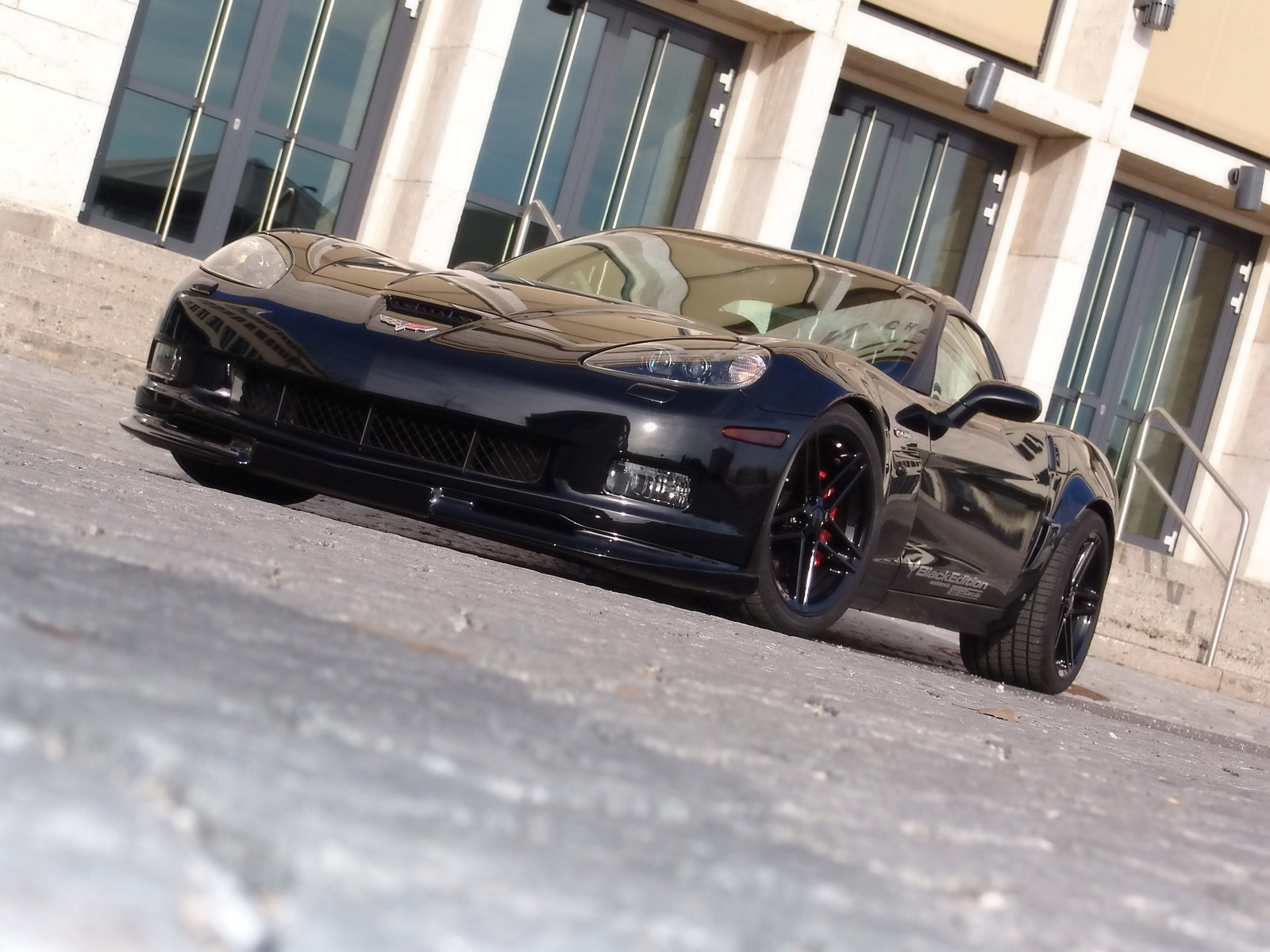 Black Chevrolet Corvette with sleek design and vibrant color, speeding on an open road.