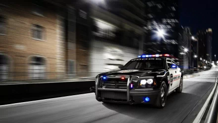A high-resolution 4K Ultra HD wallpaper showing a police vehicle speeding through a city street at night with flashing lights.