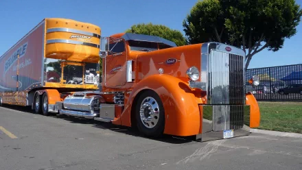 HD desktop wallpaper of a striking orange truck parked on a street with trees in the background.