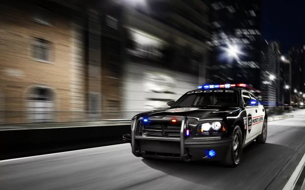 A high-resolution 4K Ultra HD wallpaper showing a police vehicle speeding through a city street at night with flashing lights.