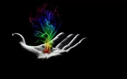 A captivating HD desktop wallpaper featuring a hand emanating colorful smoke and fire against a dark background, showcasing an artistic blend of light and shadow.